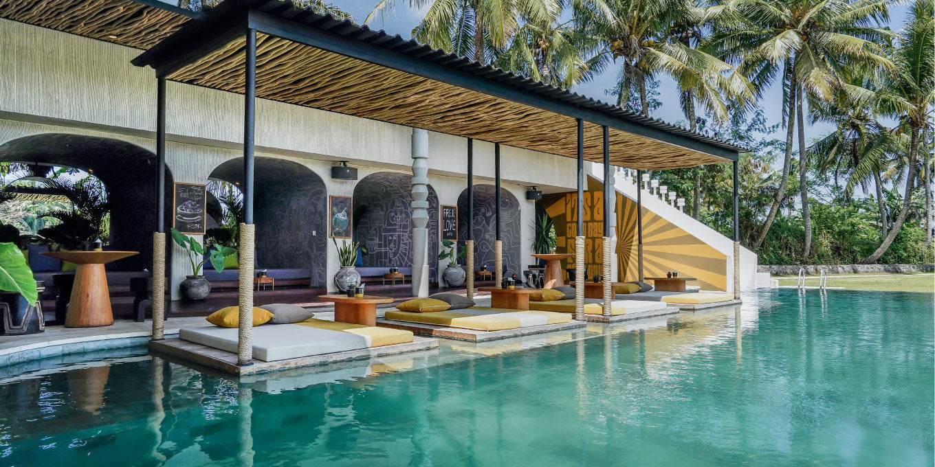 Outdoor relaxation area with pool, lounge chairs, and palm trees, Yume lifestyle
